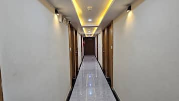 Pasillo de hotel con puertas de madera, suelo de mármol e iluminación empotrada.