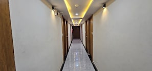 A hotel corridor with wooden doors, a marble floor, and recessed lighting. - Hotel Crystal N (Gandhinagar)