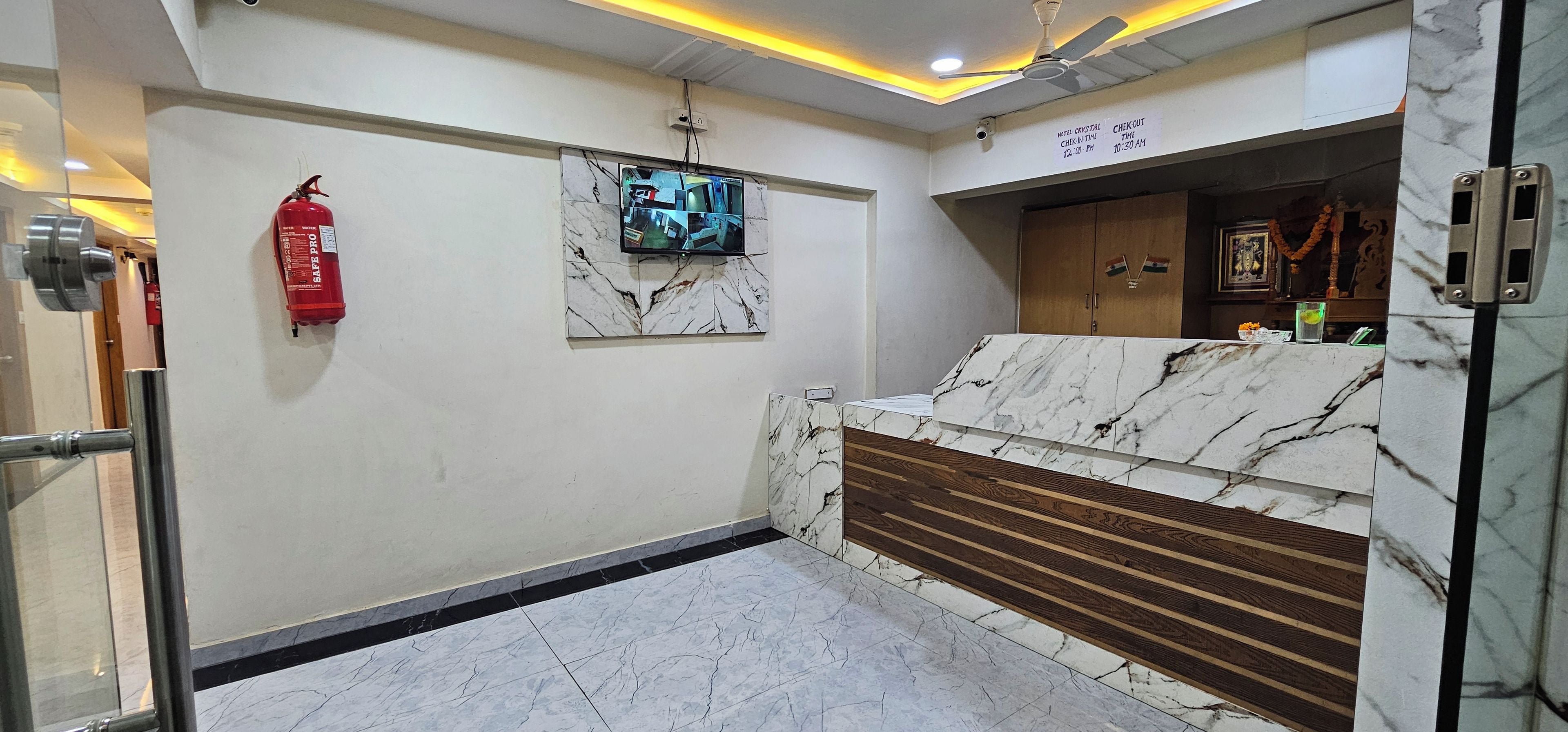A hotel lobby with a marble reception desk, a fire extinguisher, and a security camera.