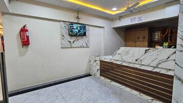 A hotel lobby with a marble reception desk, a fire extinguisher, and a security camera.