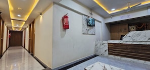 A hotel lobby with a marble reception desk, a fire extinguisher, a security camera, and a ceiling fan. - Hotel Crystal N (Gandhinagar)