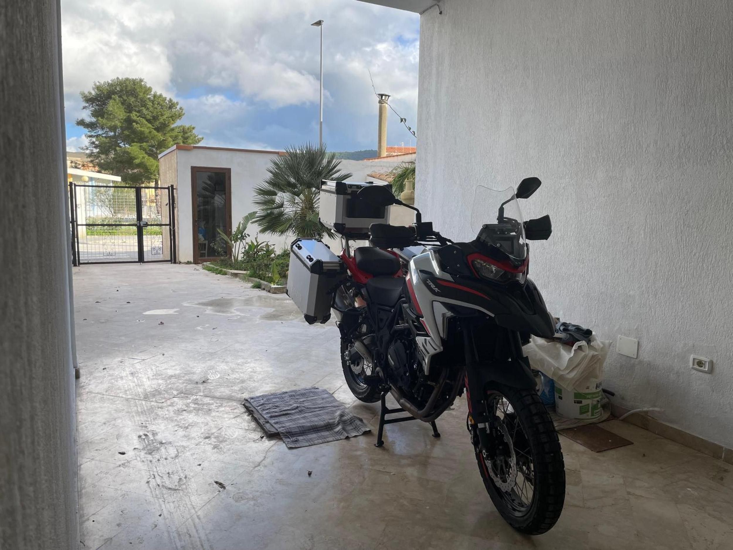 Una motocicleta estacionada dentro de un edificio con piso de concreto y vista al exterior.