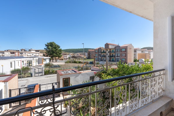 A balcony with a view of a residential area, including buildings and a tree.