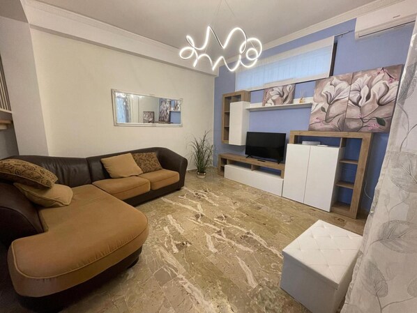 A living room with a brown sofa, a flat-screen TV, a white cabinet, and a decorative wall piece. - Holiday Home 'Dai Maestri Rubino' with Mountain View, Wi-Fi and Air Conditioning (Vita)