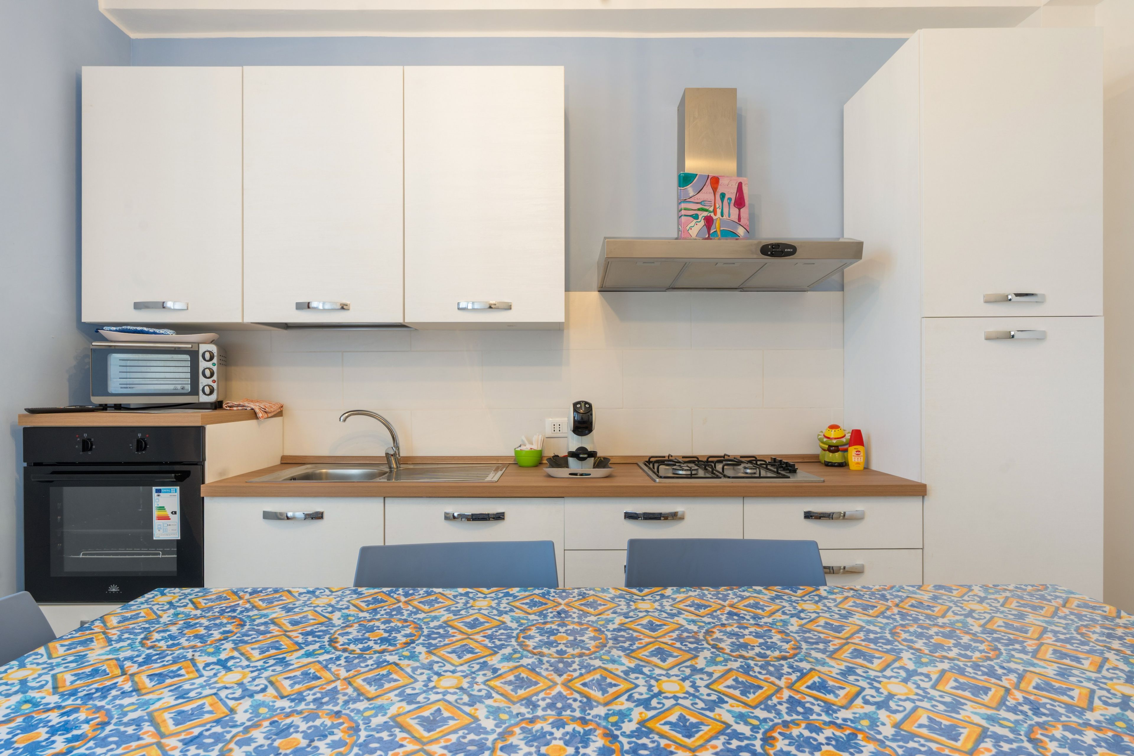 Una cocina compacta con armarios blancos, horno empotrado, cocina a gas y microondas.