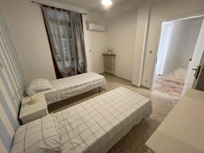 A small, clean room with two single beds, a bedside table, a radiator, and a door leading to another room. - Holiday Home 'Dai Maestri Rubino' with Mountain View, Wi-Fi and Air Conditioning (Vita)
