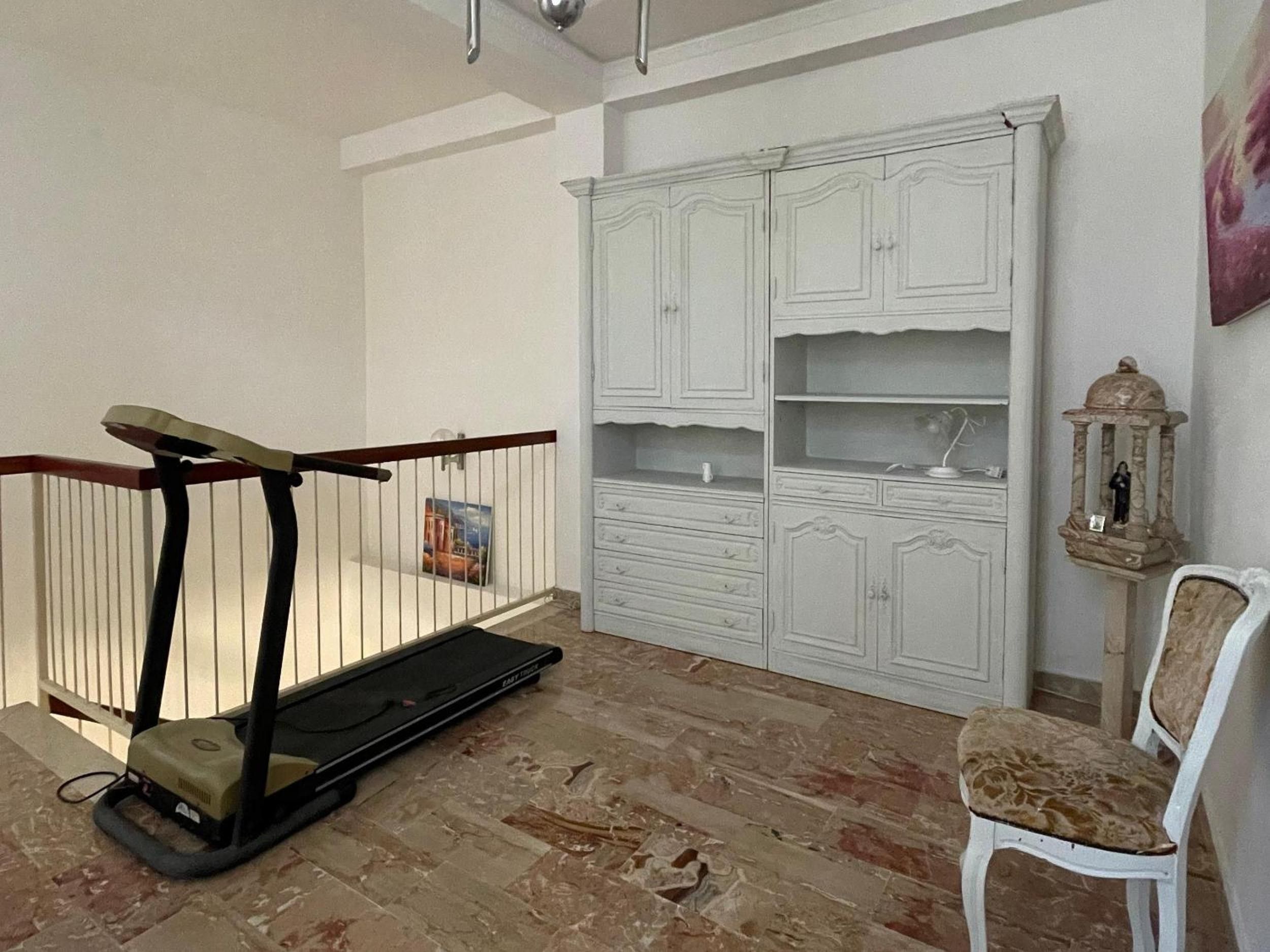 Una habitación con un armario blanco, una silla y un andador para bebé.