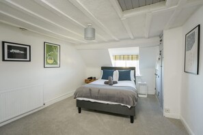 Een slaapkamer met een bed, een radiator en kunstwerken in lijsten aan de wanden.