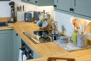 Eine Küche mit Holzausziehtisch, einer Kaffeemaschine, einem Toaster und verschiedenen Küchenutensilien.
