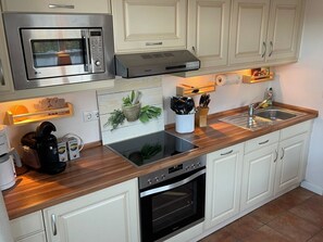 A kitchen with a microwave, oven, and sink. There are cabinets, a countertop, and a backsplash with a plant. - Deichhof Apt. 23 (Dunsum)