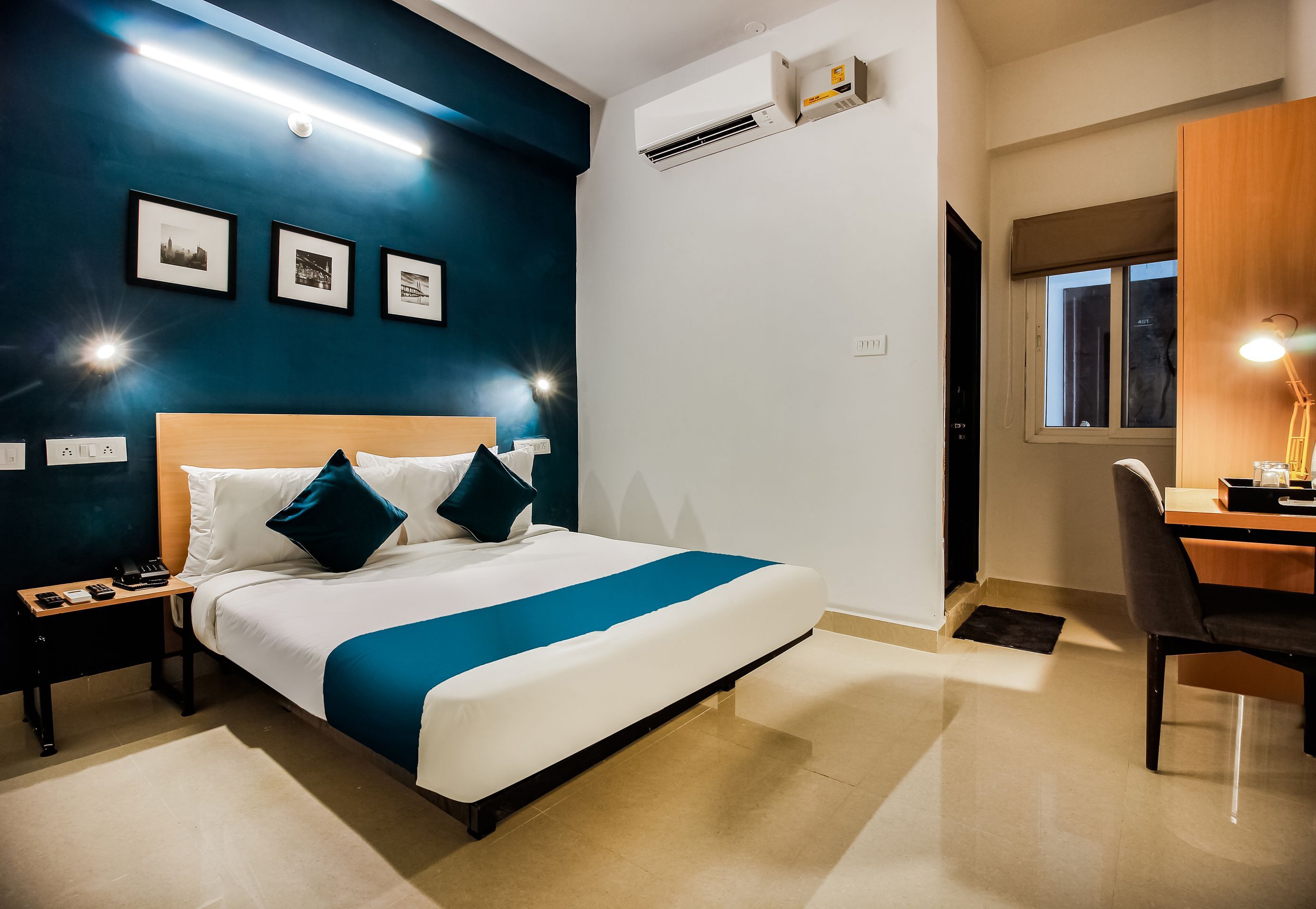 Quarto de hotel com cama, mesas de cabeceira, escrivaninha e uma cadeira.
