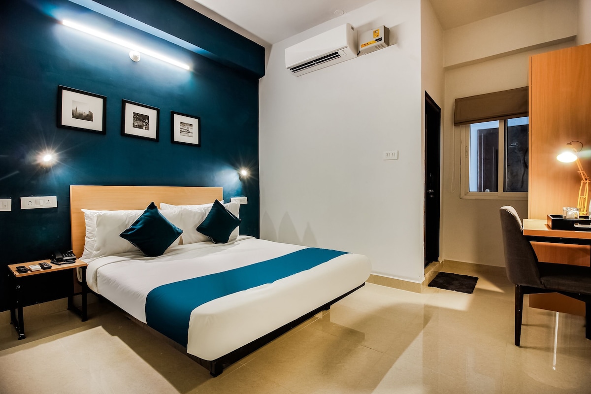 A hotel room with a bed, bedside tables, a desk, and a chair.