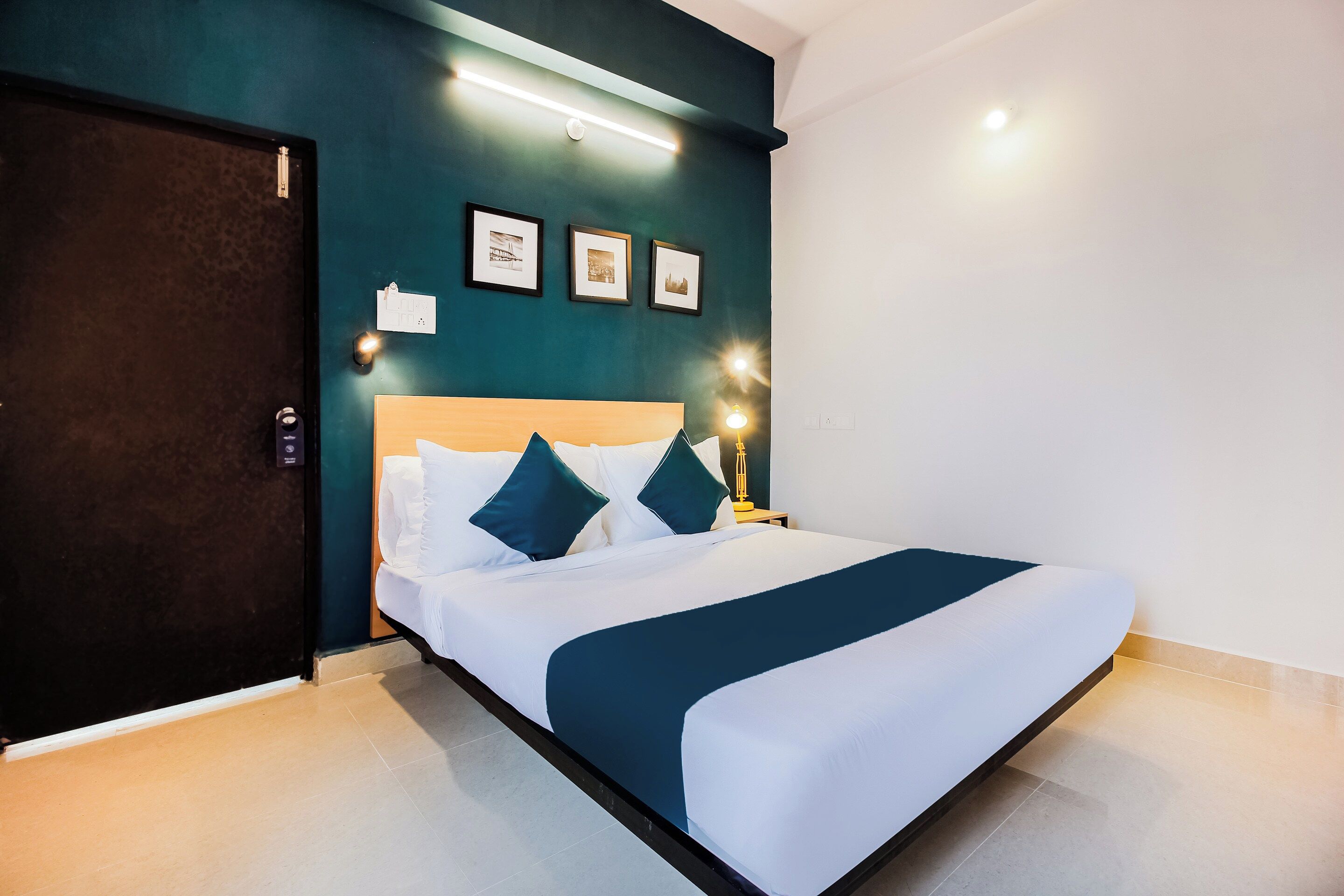 A hotel room with a bed, bedside lamps, a door, and wall-mounted lights.