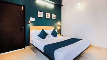 Una habitación de hotel con cama, lámparas de noche, una puerta e iluminación en la pared.