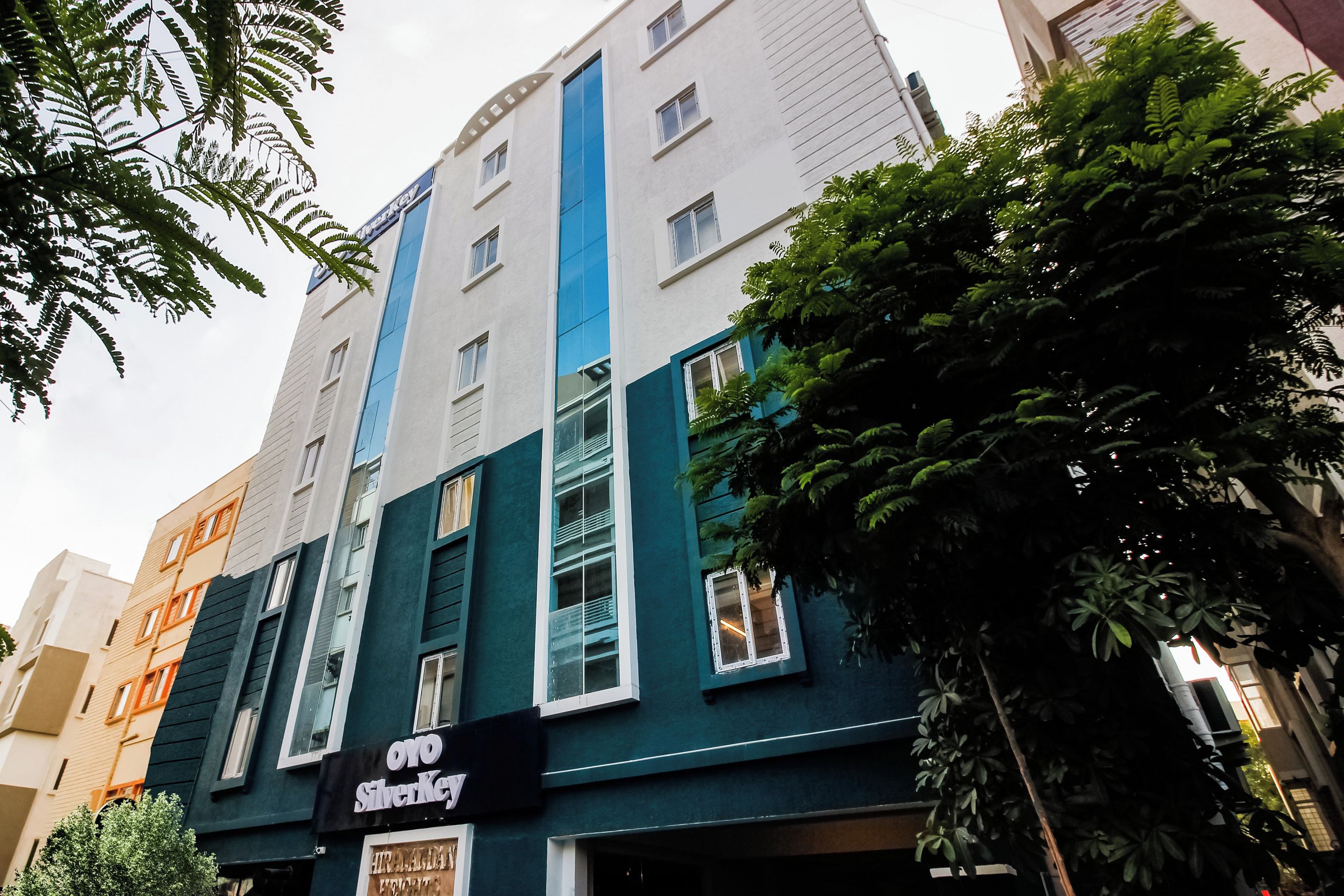 Edifício de vários andares com fachada azul e branca marcante, exibindo uma placa com 'Oyo SilverKey'.