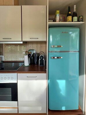 A kitchen with a turquoise Amica refrigerator, a white stove, and a wooden countertop. - Holiday home with enclosed garden and terrace (Græsted)