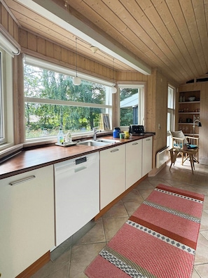 A kitchen with a large window, a sink, and a countertop with various items. - Holiday home with enclosed garden and terrace (Gr æsted)