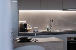 Una cocina moderna con una cafetera integrada, una copa de vino y una botella de jabón de manos sobre la encimera.
