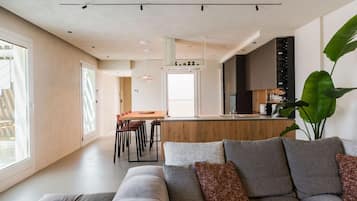 Una sala de estar moderna con un sofá gris, una mesa de centro y una planta grande.