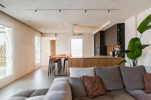 A modern living room with a grey sofa, a coffee table, and a large plant. - Micasa Jacuzzi & Rooftop Sicilymyhome (Noto)