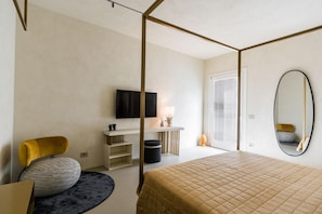 A bedroom with a bed, a television, a desk, a chair, a mirror, and a window with blinds. - Micasa Jacuzzi & Rooftop Sicilymyhome (Noto)