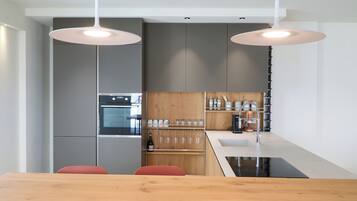 A modern kitchen with a central island, wooden cabinets, and a built-in oven.