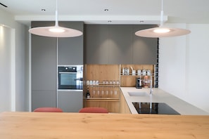A modern kitchen with a central island, wooden cabinets, and a built-in oven. - Micasa Jacuzzi & Rooftop Sicilymyhome (Noto)