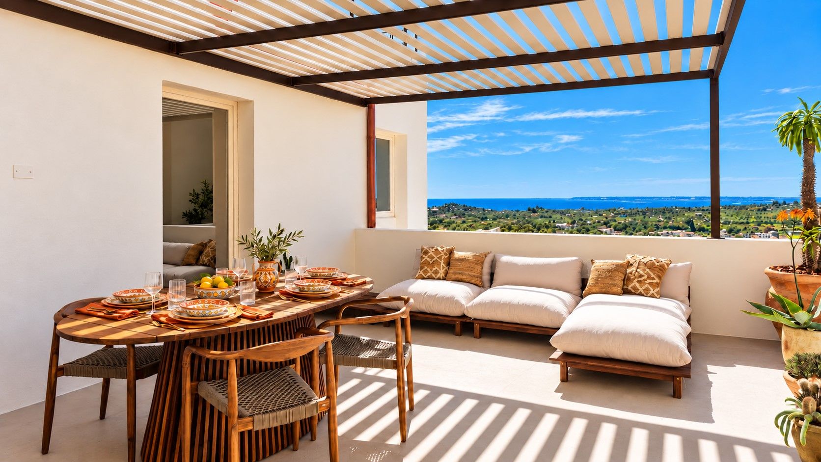 Une terrasse avec une table à manger pour quatre personnes, un canapé avec des coussins et une vue sur la mer.