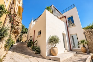 Un edificio moderno con facciata in pietra, tetto piano e un piccolo balcone.
