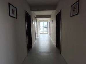 A long, narrow hallway with doors on both sides leading to rooms. - Classic Nilay Inn (Pandharpur)