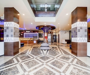 A hotel lobby with a central column, a reception desk, and a patterned floor. - Classic Hotel Nirmal Residency (Bhopal)