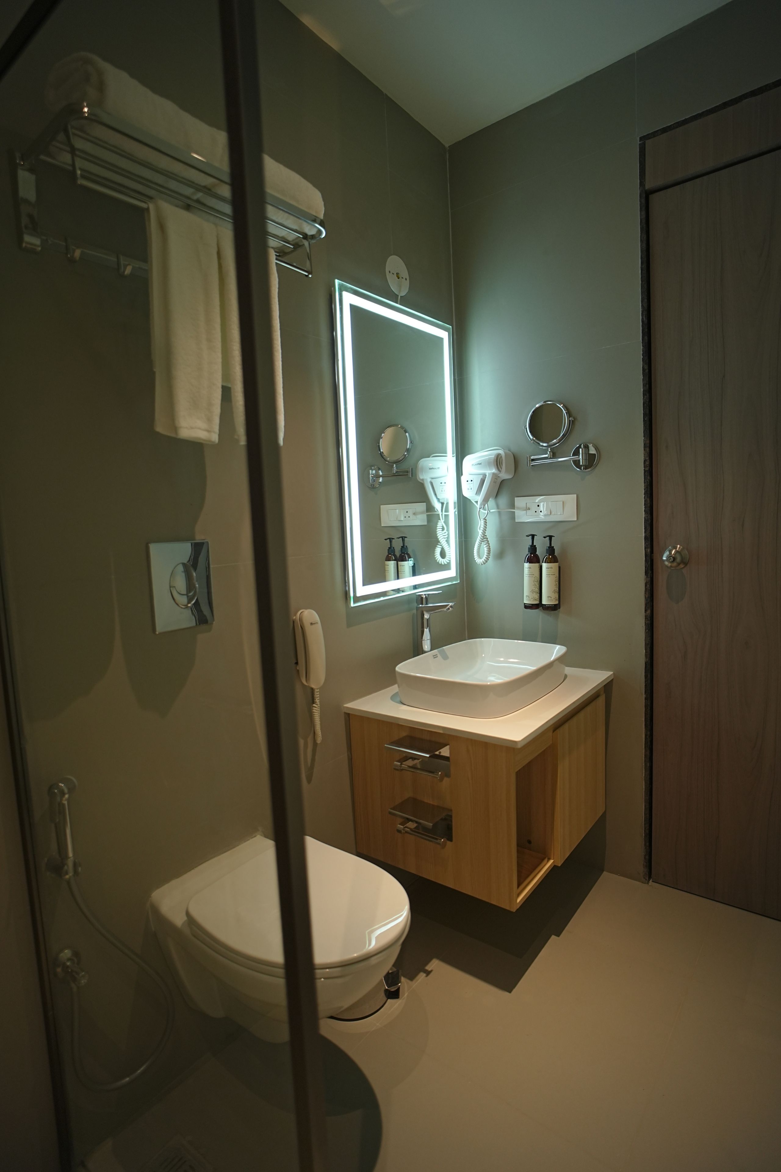Un baño moderno con inodoro, lavamanos y perchero para toallas.