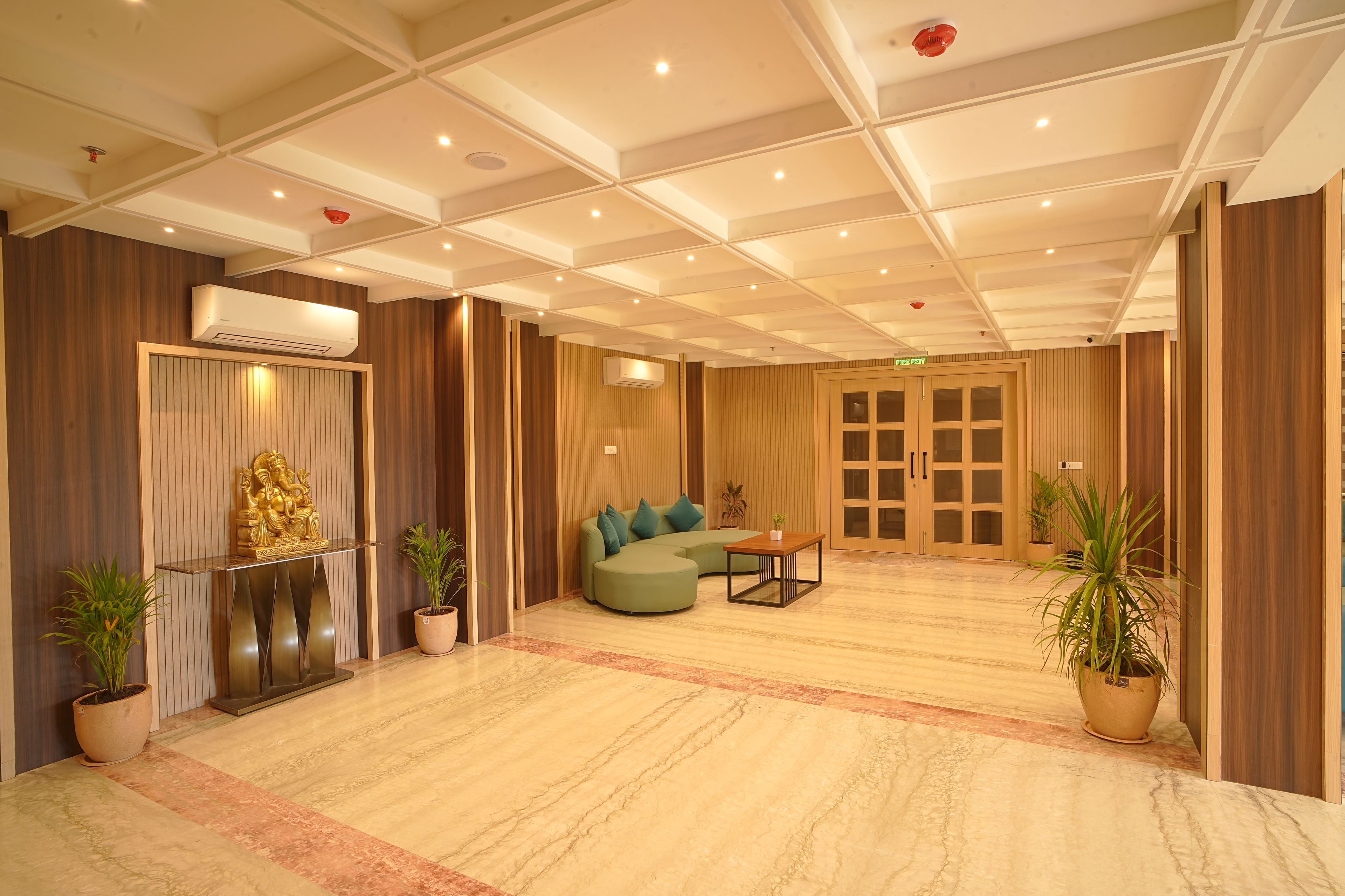 A hotel lobby with a reception desk, seating area, and a large door.
