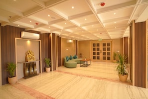 A hotel lobby with a reception desk, seating area, and a large door.