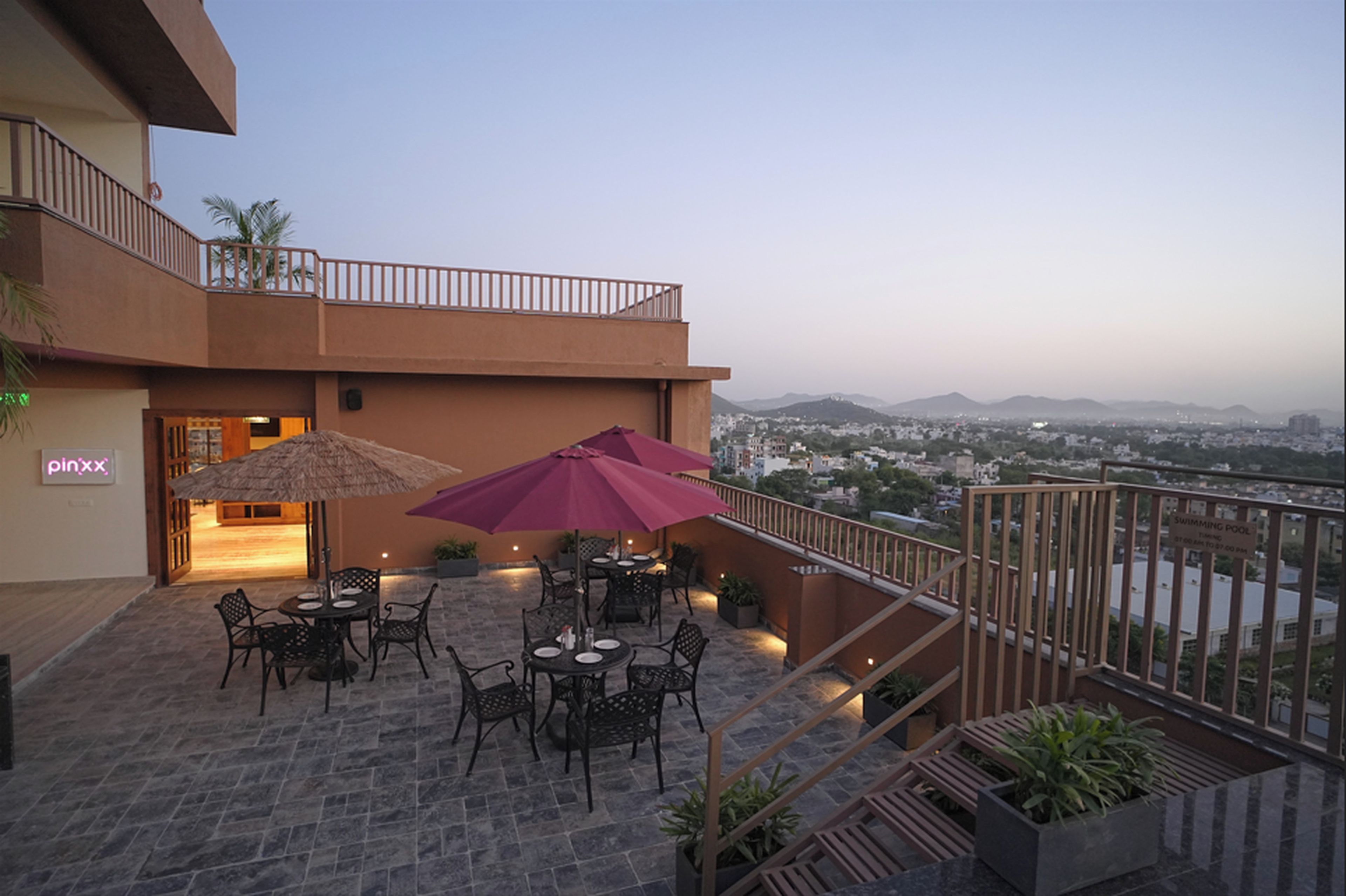 Una terraza en la azotea con mobiliario exterior, vistas de la ciudad y una piscina.