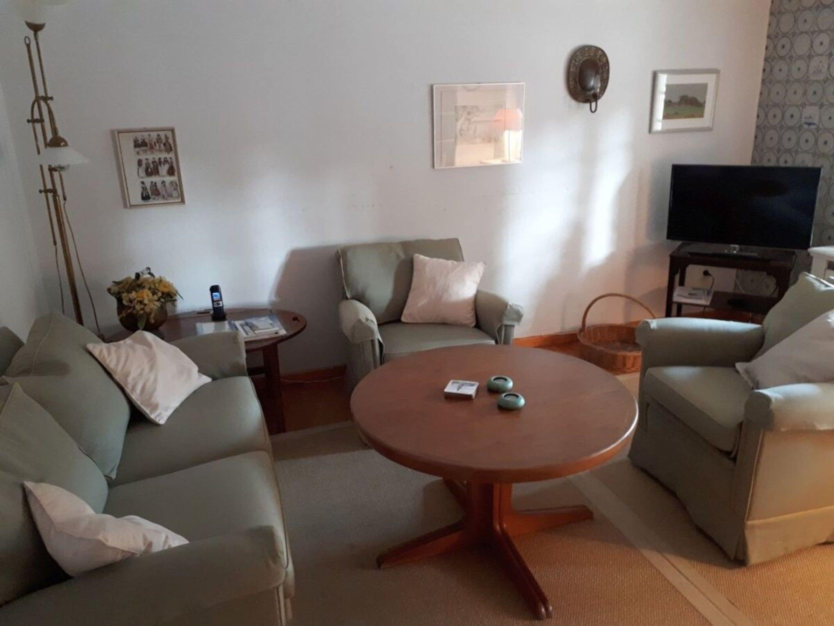 A living room with a sofa set, a coffee table, a television, and a wall-mounted picture.