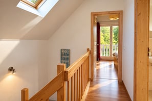 En trætrap fører op til en balkon med udsigt over grønne områder.