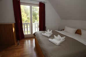 Ein Schlafzimmer mit einem Bett, einem Holzschrank und Blick ins Freie durch eine Schiebetür.