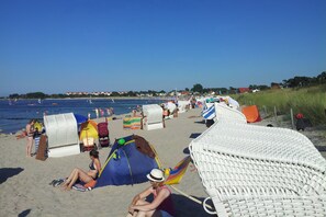 A beach with beach chairs and umbrellas, a tent, and a few people. - Wellenläufer Vacation Home in Glowe – Sauna, Fireplace & Baltic Sea Vacation (Glowe)