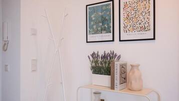 A minimalist room with a white wall, a white metal shelf, and two framed artworks.