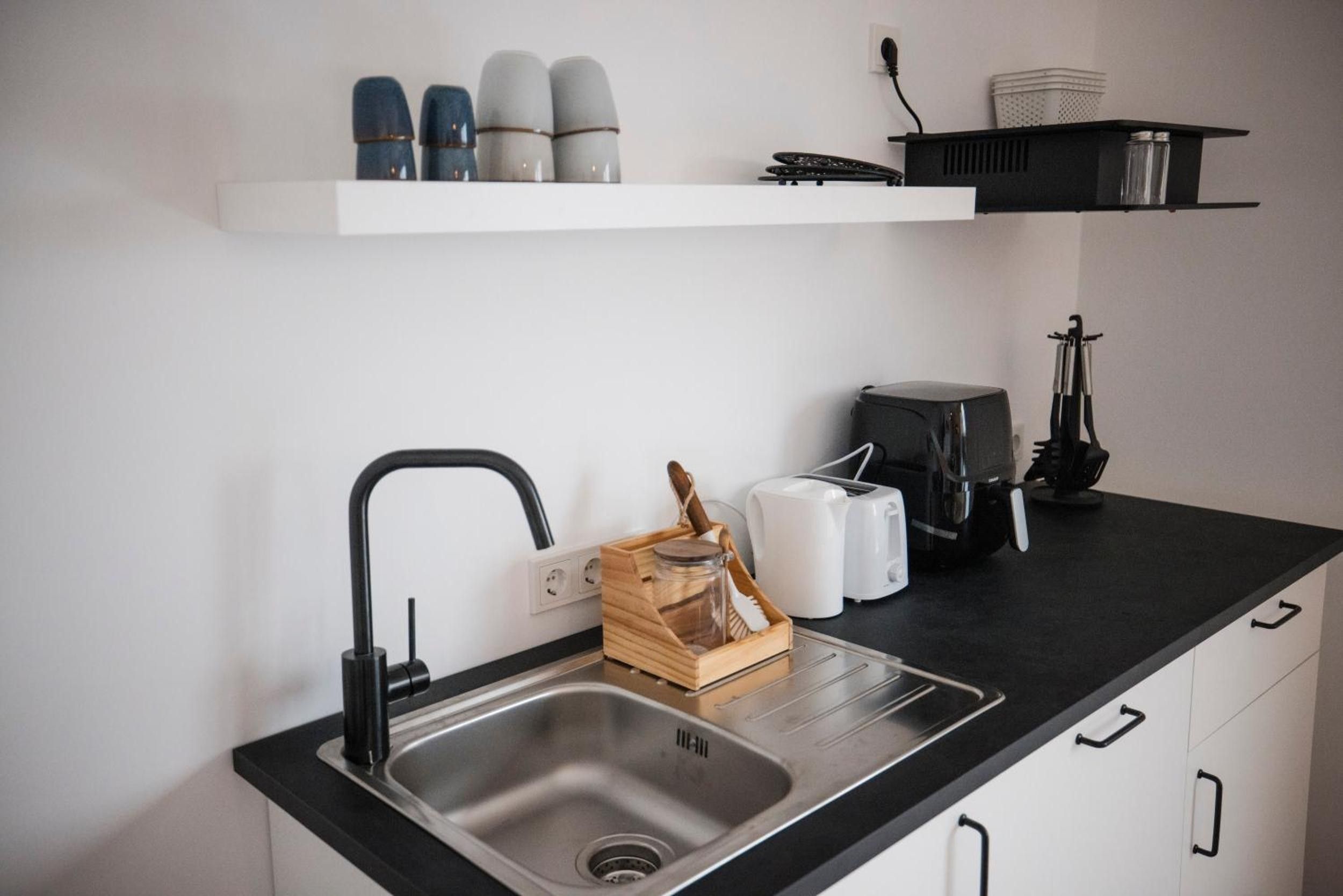 A modern kitchen with a stainless steel sink, a toaster, and a coffee maker on the countertop.