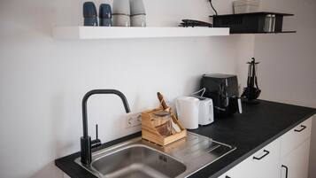 A modern kitchen with a stainless steel sink, a toaster, and a coffee maker on the countertop.