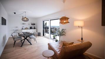 A modern living space with a dining area, a sofa, a coffee table, and a balcony with a view.