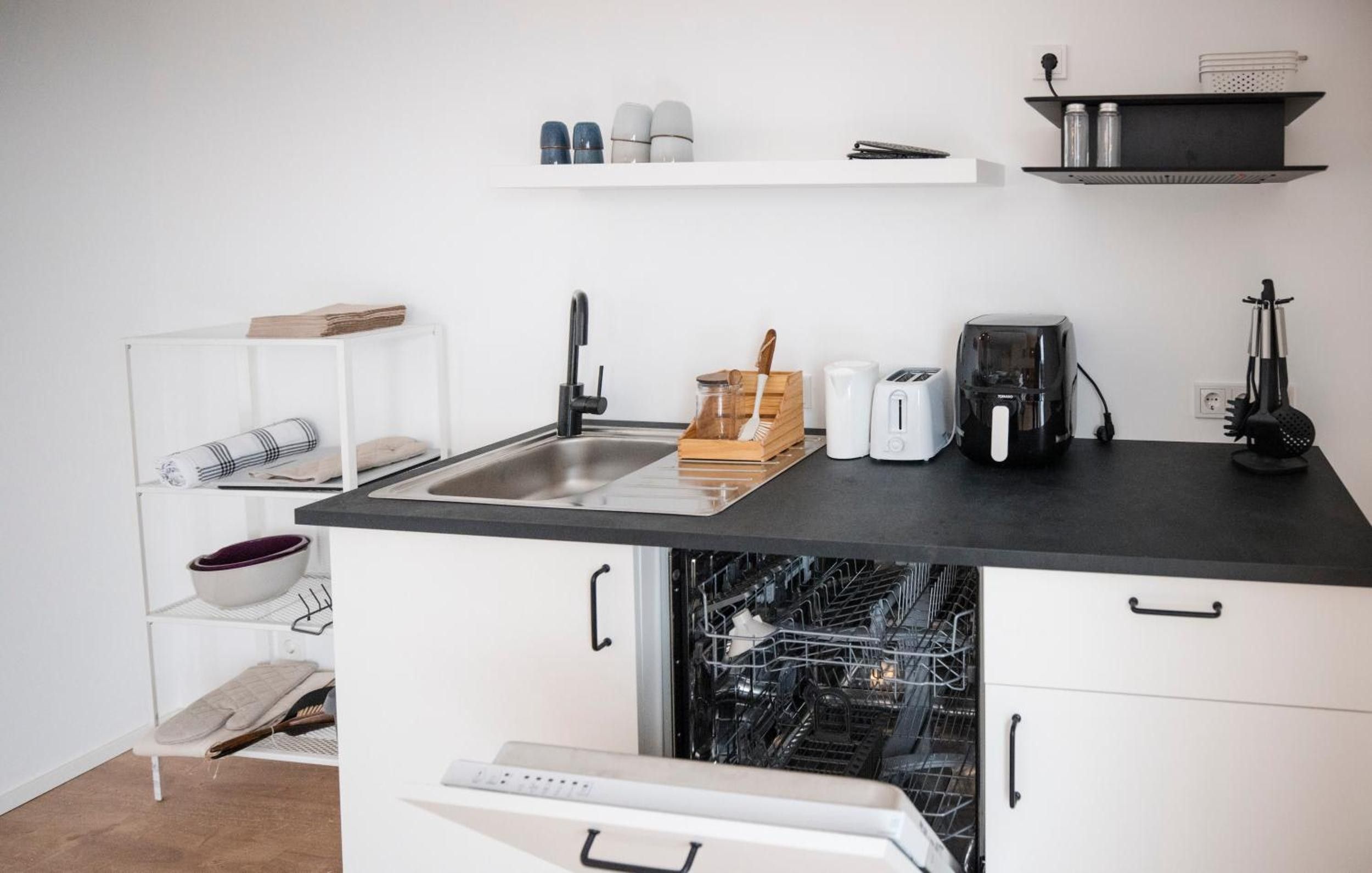 Eine kompakte Küche mit Geschirrspüler, Toaster und Kaffeemaschine.