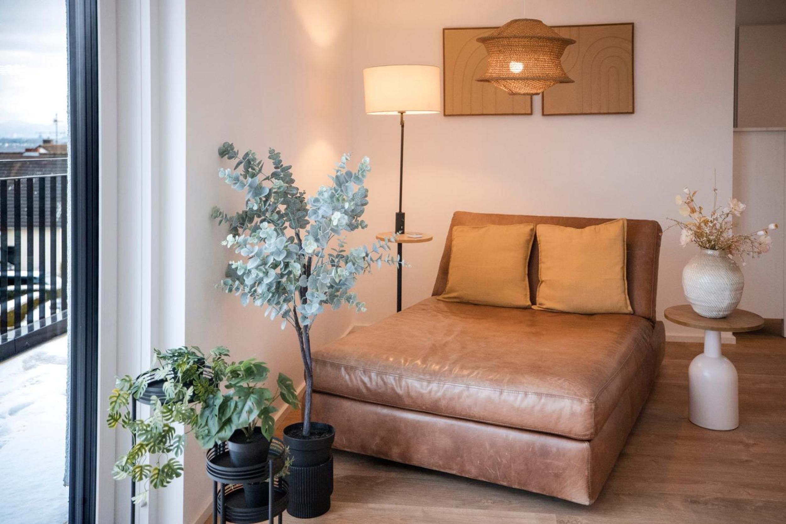 Ein Schlafzimmer mit einer Ledersofa, einem Nachttisch mit Lampe und einer Topfpflanze.