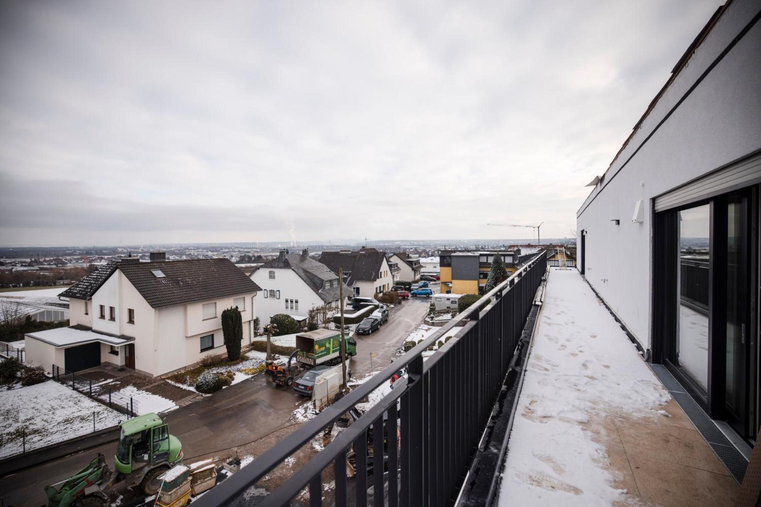 Ein Wohngebiet mit Häusern, einer Straße und einem schneebedeckten Balkon.