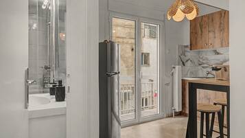 A modern kitchen with a refrigerator, a sink, and a dining area with stools.
