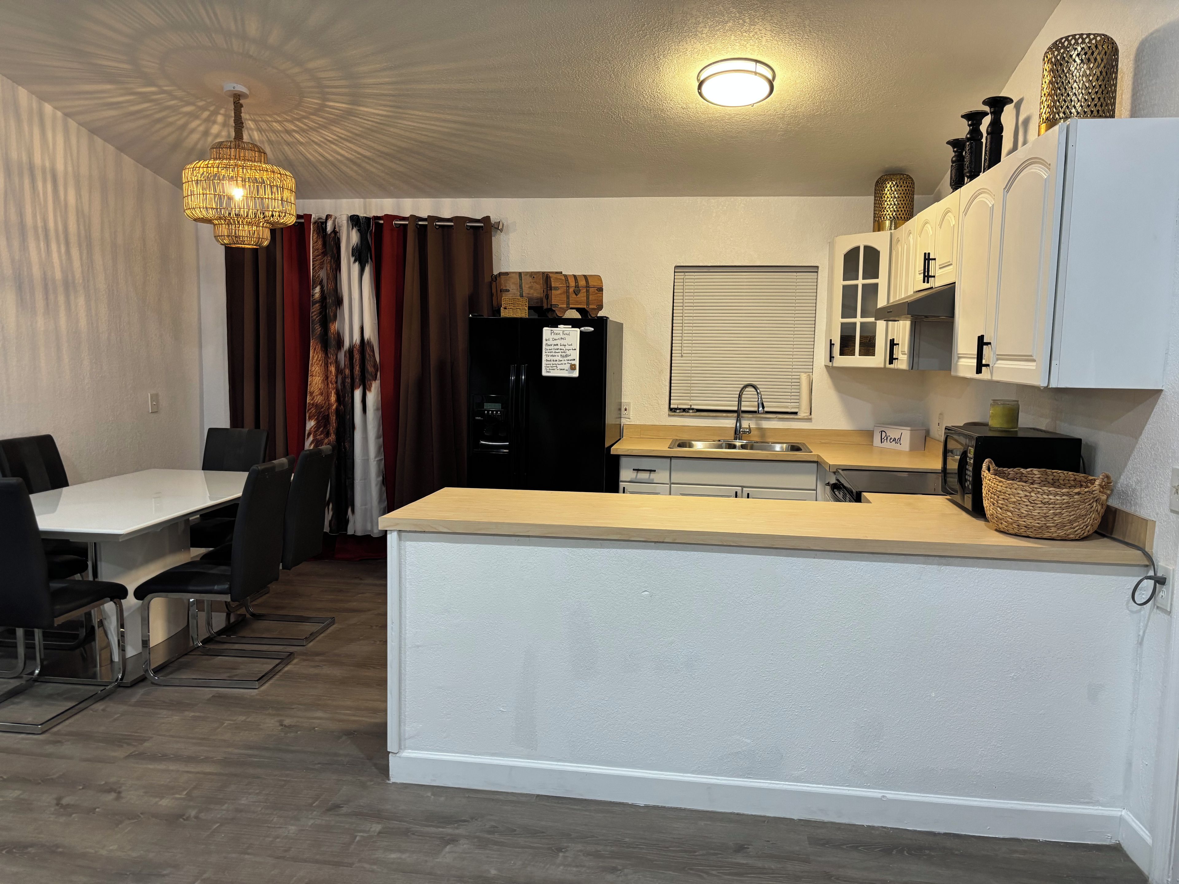 Cocina compacta con comedor, que incluye refrigerador, microondas, lavamanos y una araña.
