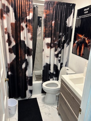 Ein Badezimmer mit Duschvorhang, Toilette, Waschbecken und einem Poster an der Wand.