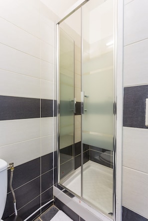 A shower area with a glass door, tiled walls, and a visible shower control panel. - Welcoming Apartment -1br/6p - Auteuil / Passy (Paris)